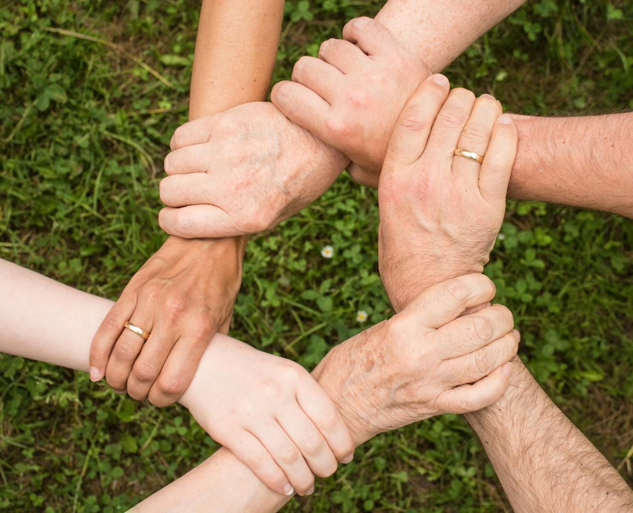 services-img Close-up of diverse hands forming a connection, symbolizing teamwork and unity outdoors.